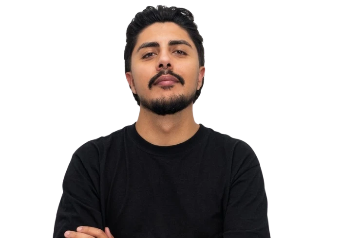 Paulo Mello, de barba e bigode, camiseta preta e braços cruzados, recortado sobre o fundo do site.